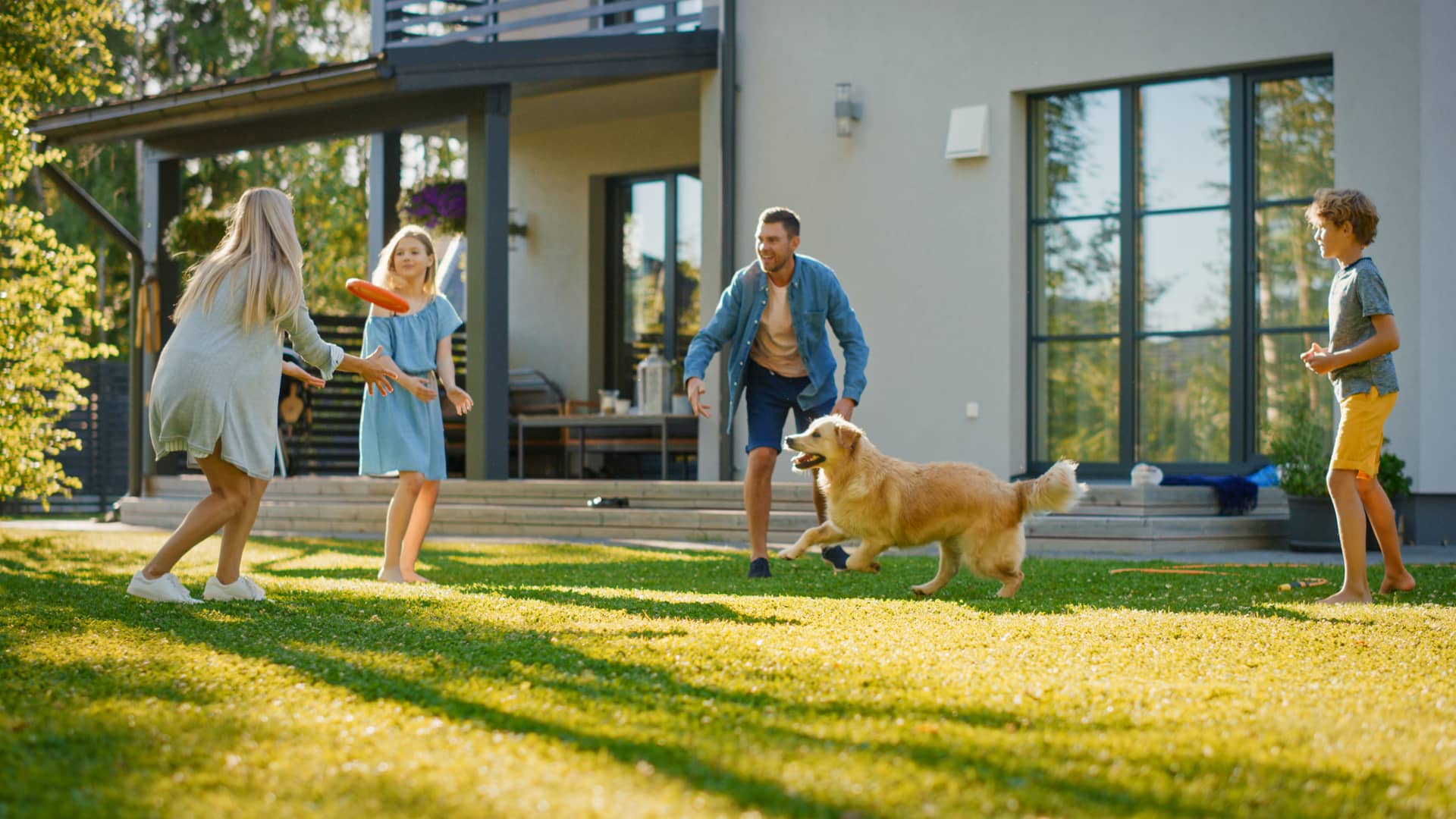 Una familia en el jardín de su casa jugando con el perro que representa las alarmas para mascoteas que puedes contratar con adt